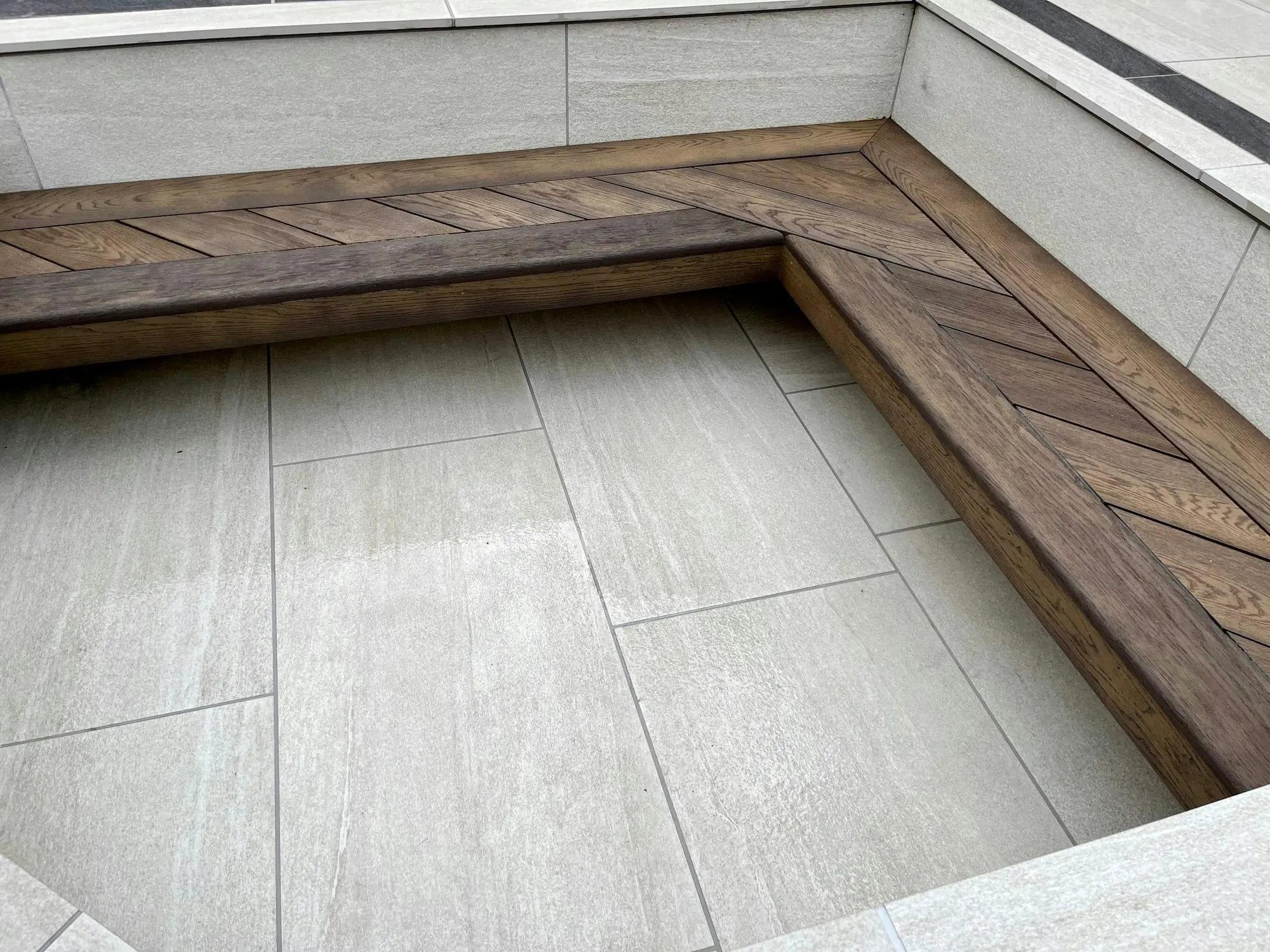 Herringbone timber corner bench built into a porcelain paved terrace