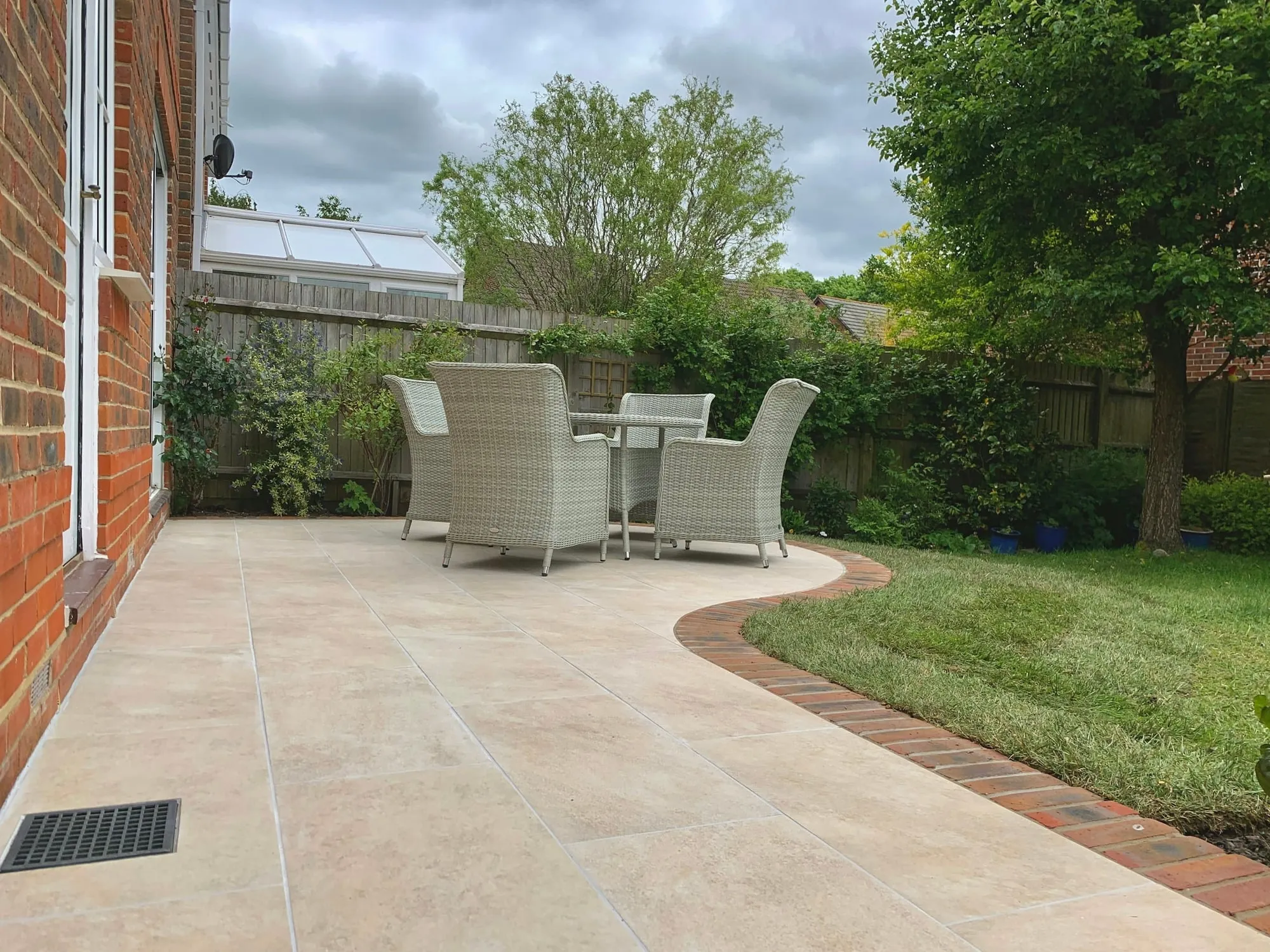 Paved terrace with garden chairs and a curved lawn edge