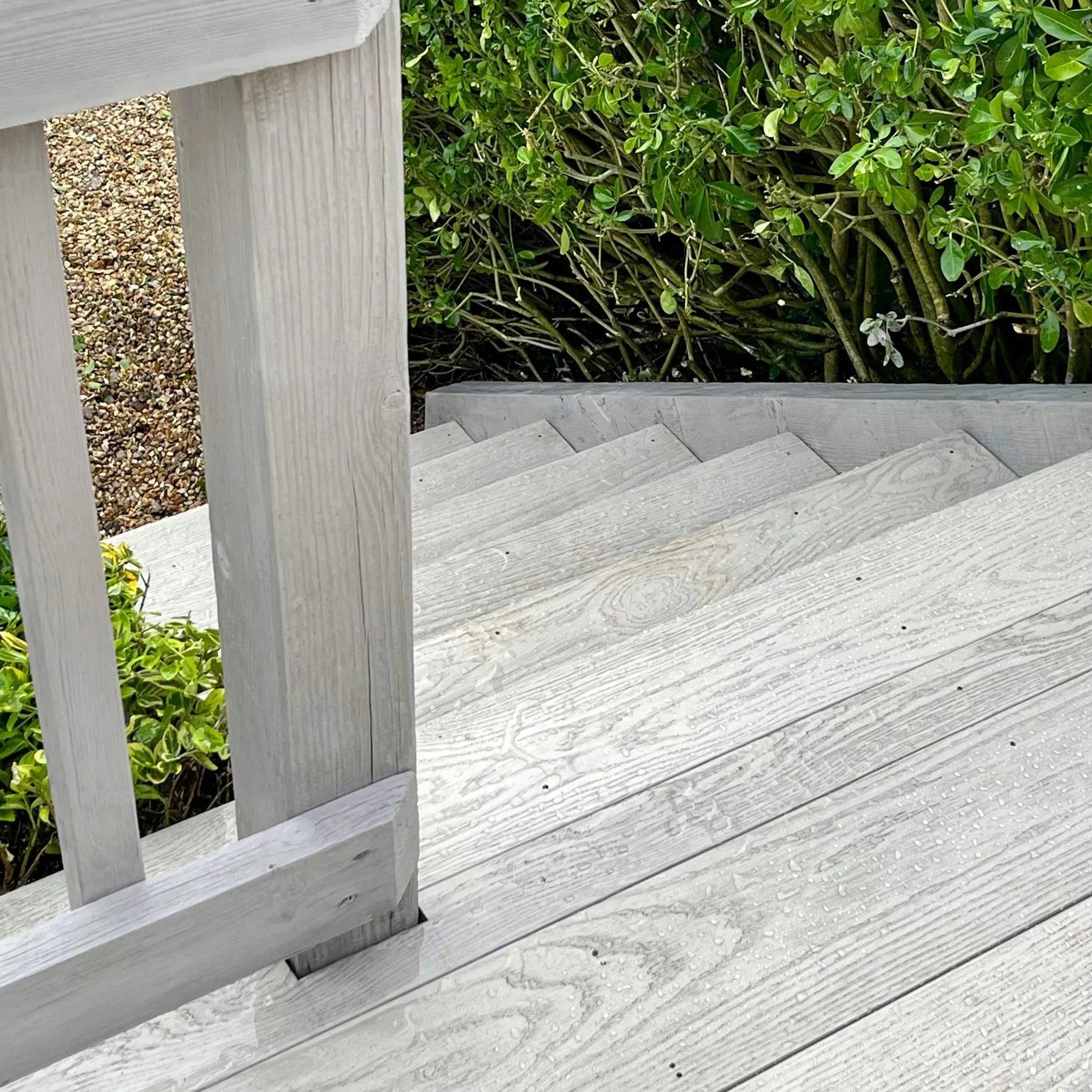 Oak post beside grey composite decking and a gravel border